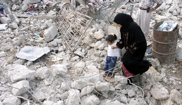 A woman and child pick their way through the rubble of their neighbourhood in Bethlehem. West Bank.